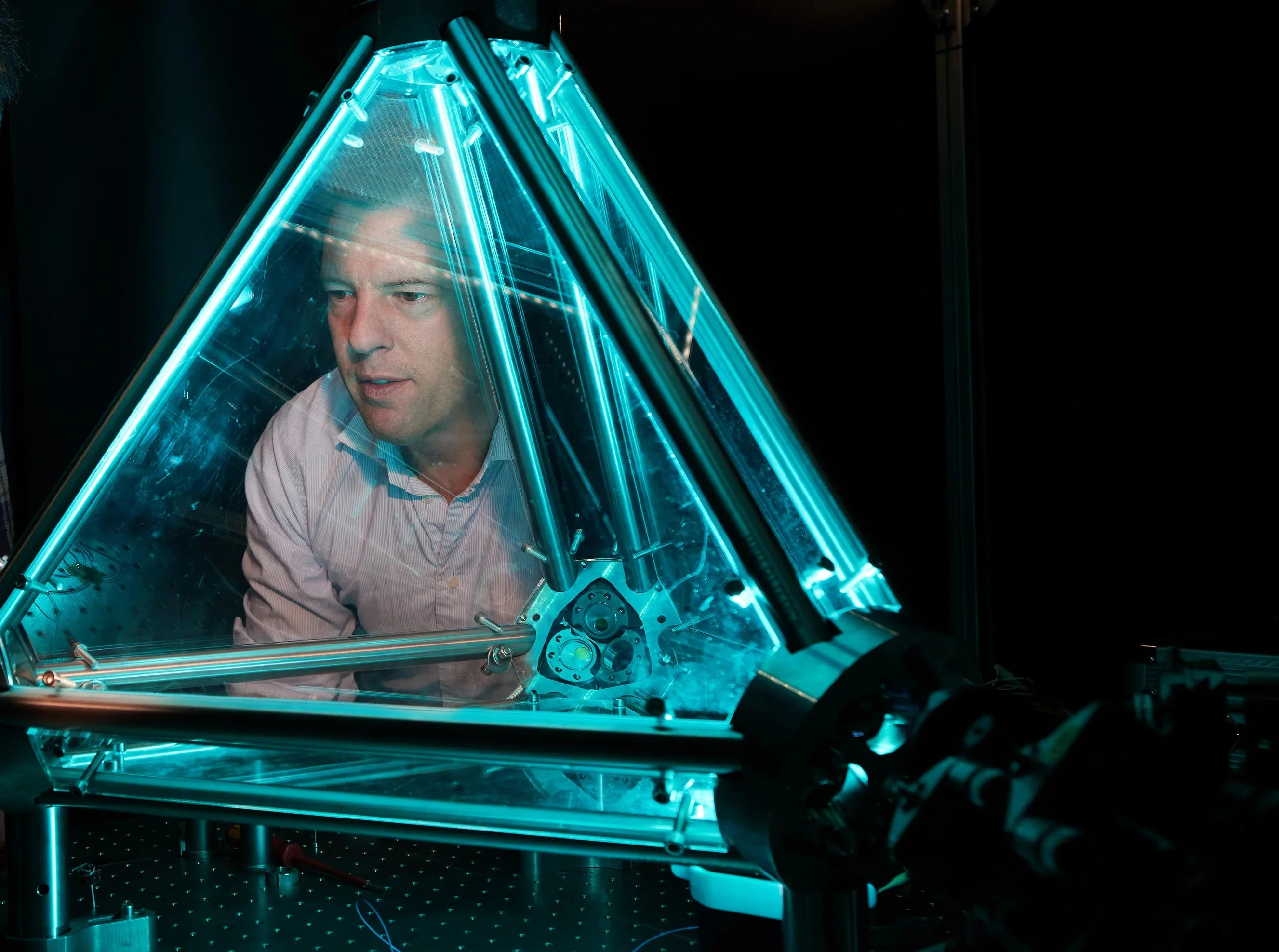 Prof. Dr. Simon Stellmer vom Physikalischen Institut der Universität Bonn hinter einem Ringlaser, der als Entwicklungsplattform für transportable Sensoren dient.
