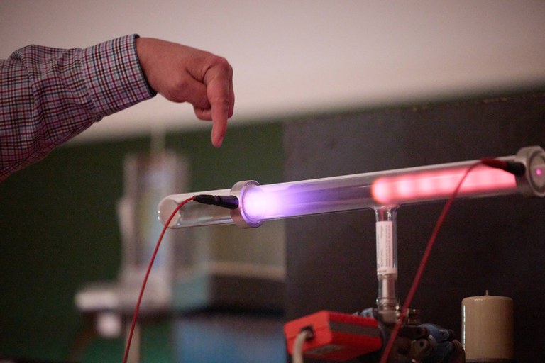 A voltage is applied and the gas atoms in the tube light up. The color of the light reveals which gas it is. A voltage is applied and the gas atoms in the tube light up. The color of the light reveals which gas it is.