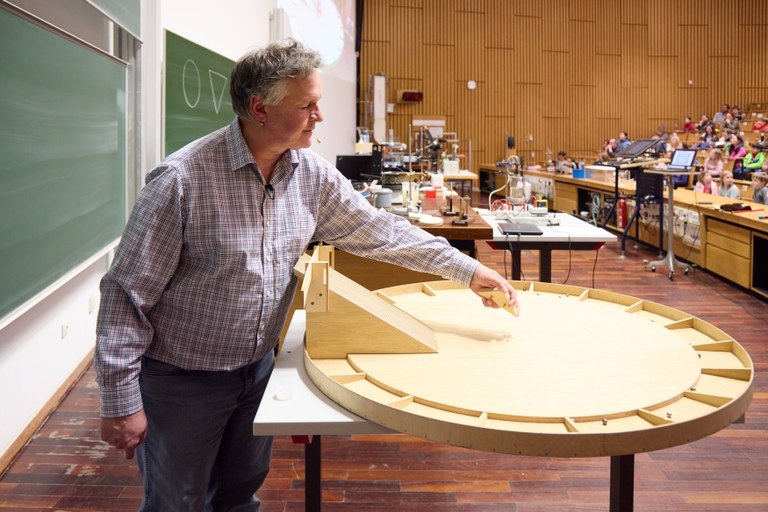 Prof. Desch positions a wooden body in the middle of a scattering board. Prof. Desch positions a wooden body in the middle of a scattering board.